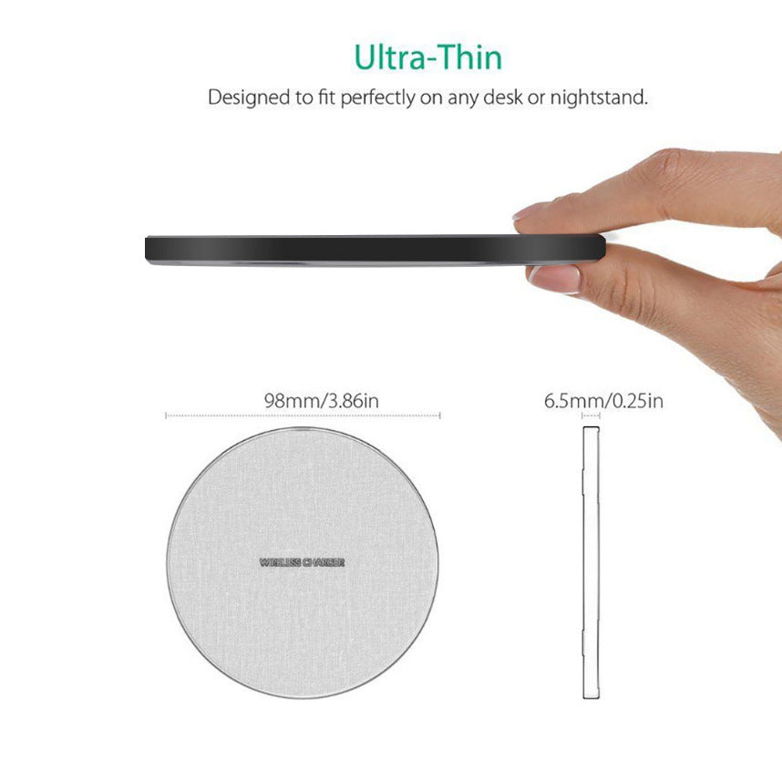 Ultra-thin black wireless charger with fabric top, 98mm diameter and 6.5mm thickness, held between fingers