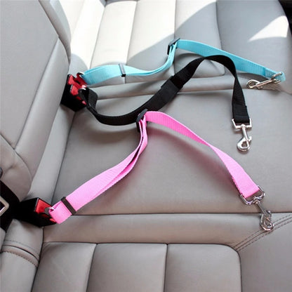 Adjustable pet car seat belts in pink, black, and blue secured to car seat belts on gray leather car seat
