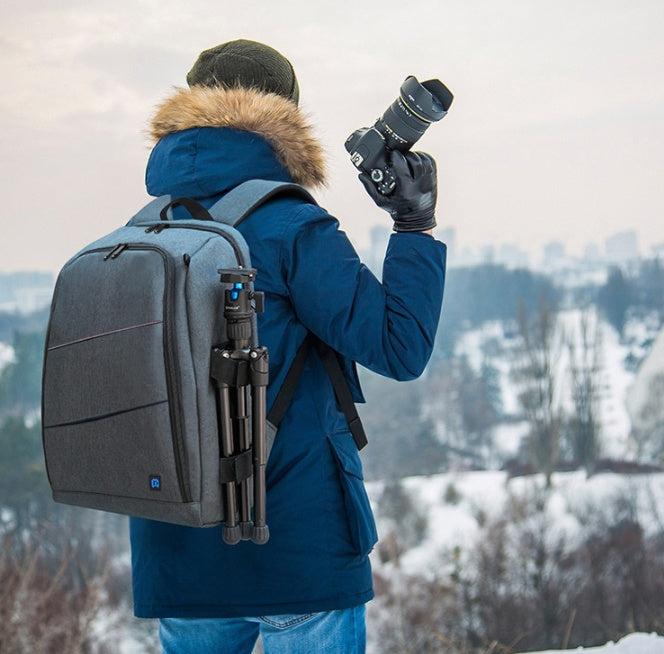 Photographer in blue jacket with fur hood carrying gray waterproof camera backpack with tripod in snowy landscape
