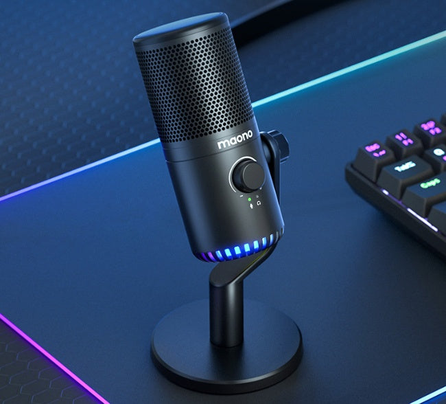 Maono black gaming microphone with volume control and blue LED on RGB mouse pad near keyboard