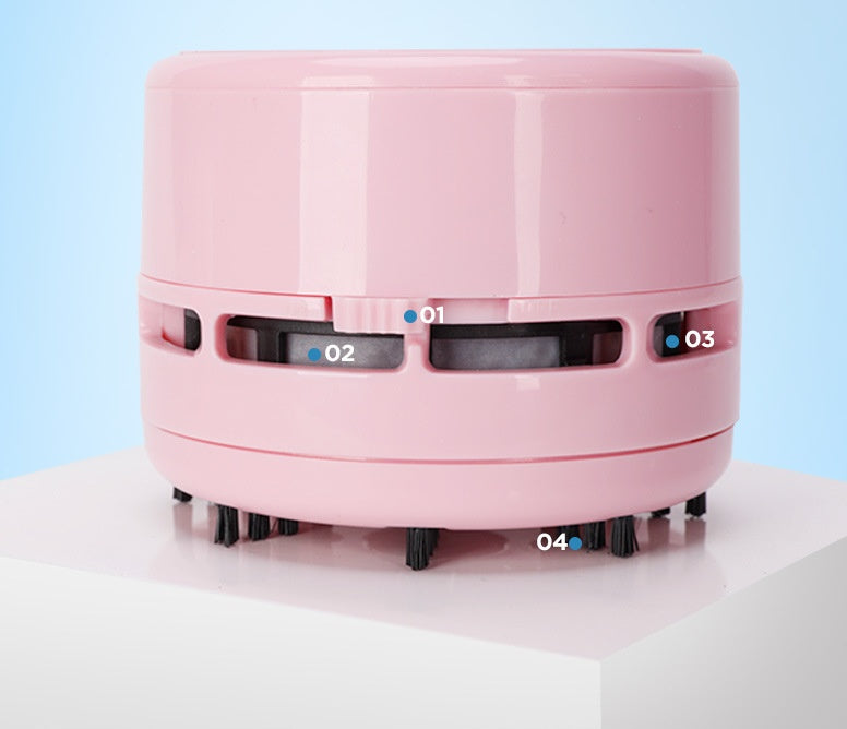 Pink mini electric desktop vacuum cleaner with round shape and black bristles on white surface