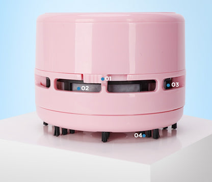 Pink mini electric desktop vacuum cleaner with round shape and black bristles on white surface