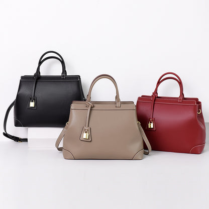 Three PU leather handbags in black, taupe, and red with top handles and gold padlock detail