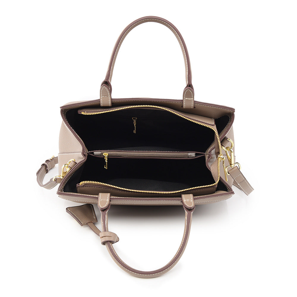 Taupe PU leather tote bag with beige stitching, dual handles, gold zippers, and roomy interior compartments