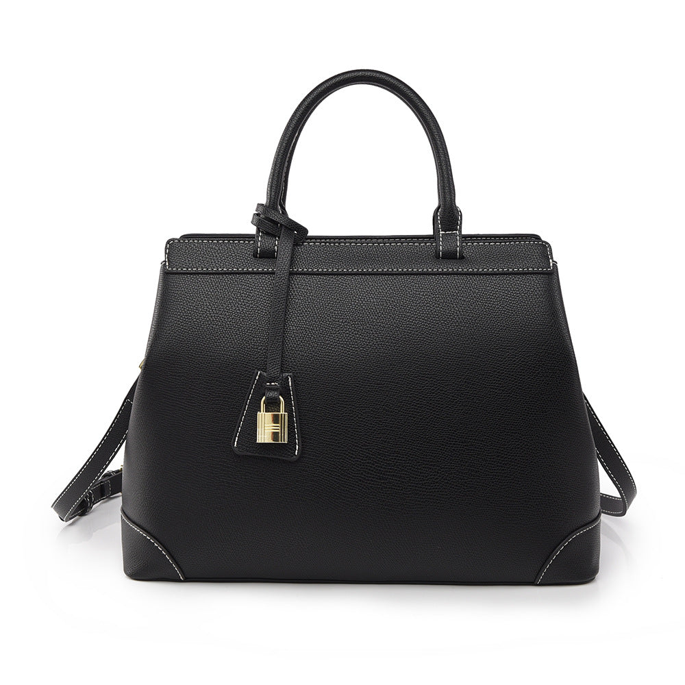 Black PU leather vertical square handbag with gold lock, handles, and white stitching