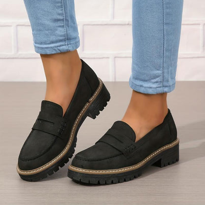 Black thick-soled women's loafers with contrast stitching worn with light blue jeans