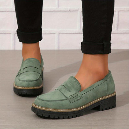 Women's sage green thick-soled loafers with lugged black sole on wooden floor