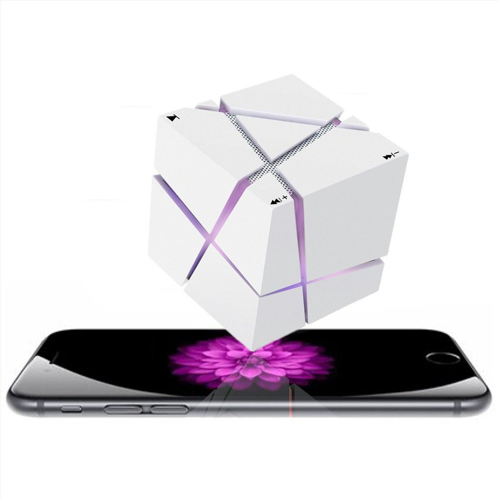 White cube Bluetooth speaker with LED lights above a smartphone with purple flower screen