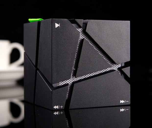 Black Trendoligy Cube Bluetooth speaker with colorful lights and angular design on reflective surface