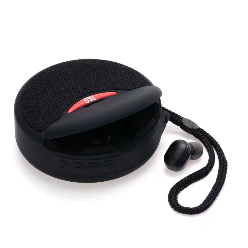 Black round portable Bluetooth speaker with fabric top and detachable braided strap with single wireless earbud