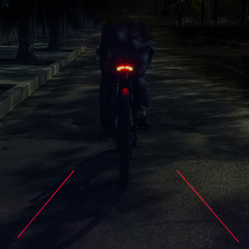 Person riding bike at night with bright red USB rechargeable smart tail light and laser lane indicators
