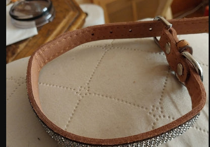 brown leather dog collar with sparkling rhinestones and silver buckle on beige quilted surface