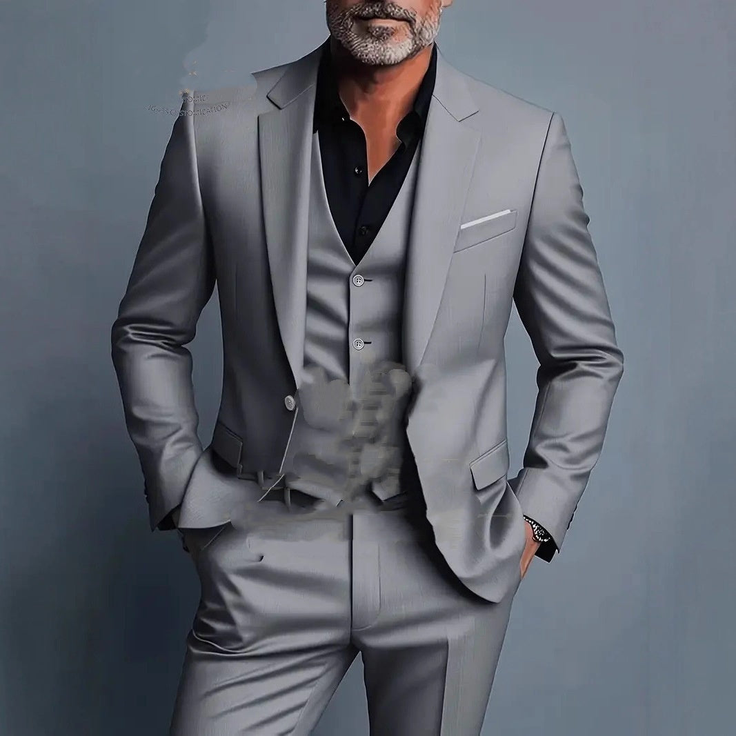 Man wearing a slim fit light gray three-piece suit with a black shirt, hands in pockets, gray background