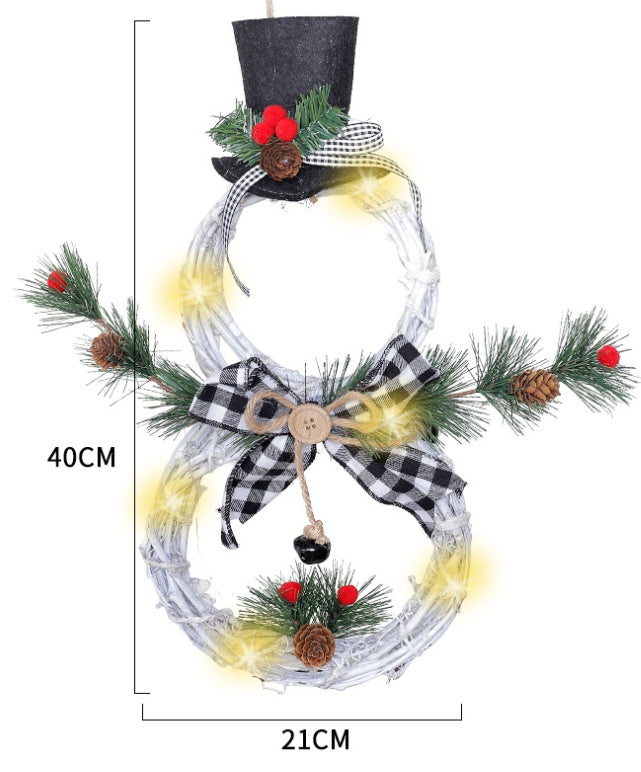 Battery-operated LED Christmas wreath shaped like a snowman with black top hat, pine cones, red berries, and plaid bow