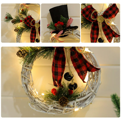 White twig Christmas wreath decorated with pinecones, red plaid bow, greenery, red berries, black jingle bells, and LED lights
