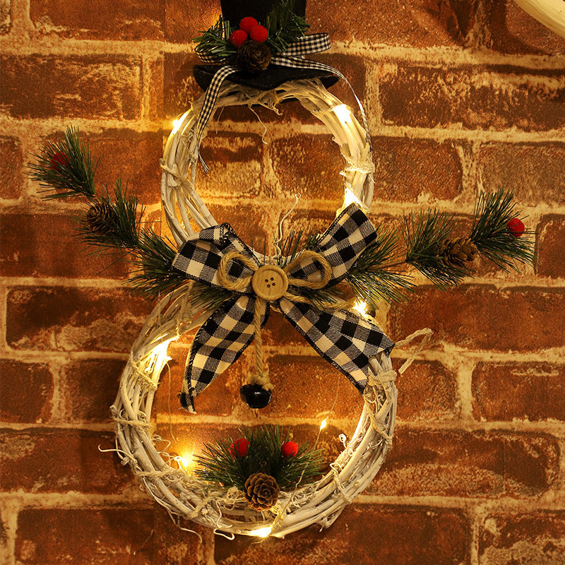 LED-lit black and white plaid bow Christmas wreath shaped like a snowman on brick wall