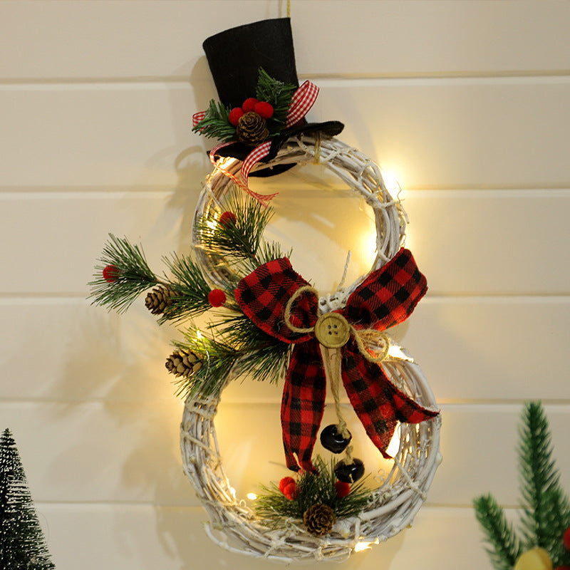 Snowman-shaped Christmas wreath with black top hat, red plaid bow, pinecones, greenery, and LED lights