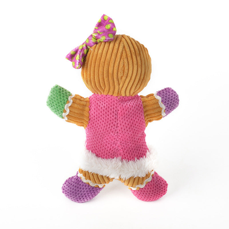 Plush gingerbread man dog toy with pink, green, and purple accents and a polka dot bow