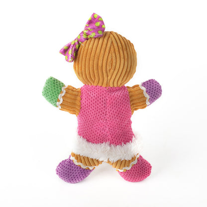 Plush gingerbread man dog toy with pink, green, and purple accents and a polka dot bow