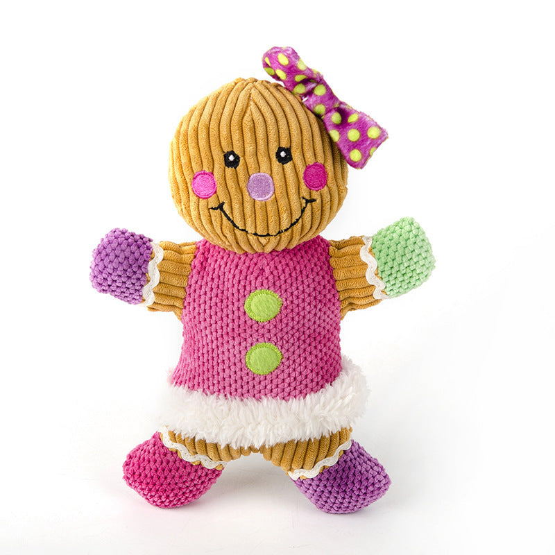 Colorful gingerbread man plush dog toy with pink vest, green polka-dot bow, and textured fabric