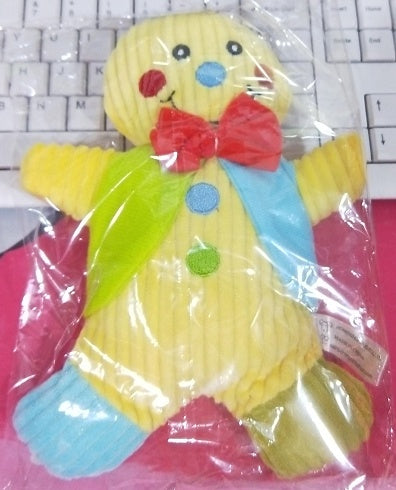 Plush yellow gingerbread man dog toy with red bow tie, colorful buttons, and soft fabric in packaging