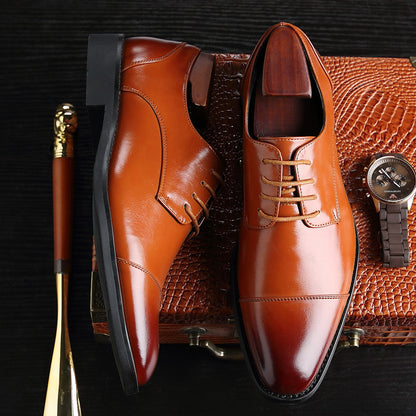 Men's brown leather business dress shoes with laces and durable soles displayed on textured brown briefcase with gold-handled cane and wristwatch