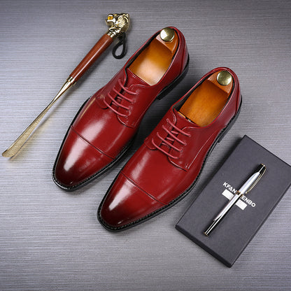 Pair of polished red men's formal dress shoes with wooden shoe trees, shoehorn with lion handle, and black pen on box