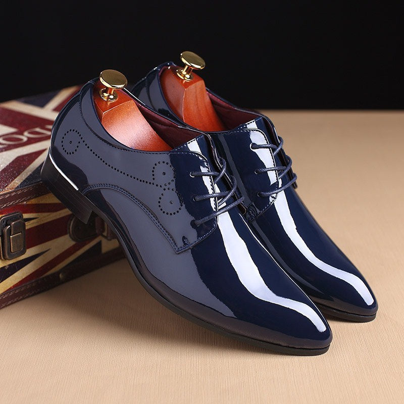 Shiny navy blue men's formal leather shoes with laces and decorative stitching, displayed on a beige surface