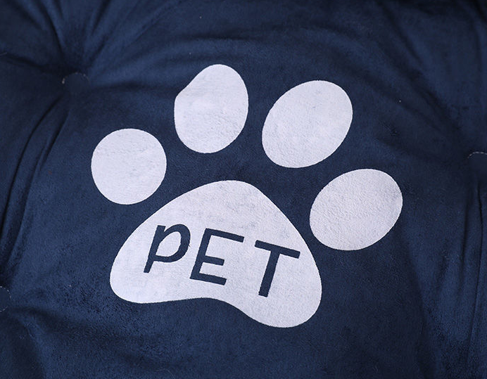 Close-up of navy blue plush pet bed with large white paw print and word PET in center