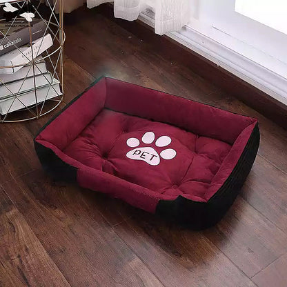 Rectangular red and black cozy pet bed with a white paw print and 'PET' text, placed on wooden floor