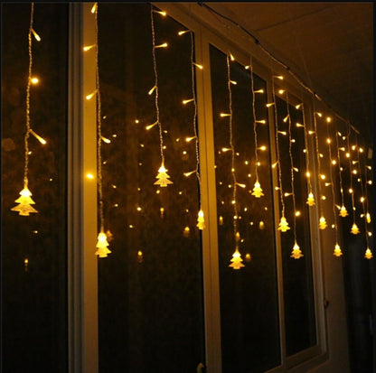 Warm yellow Christmas tree icicle string lights hanging on window at night for festive decoration
