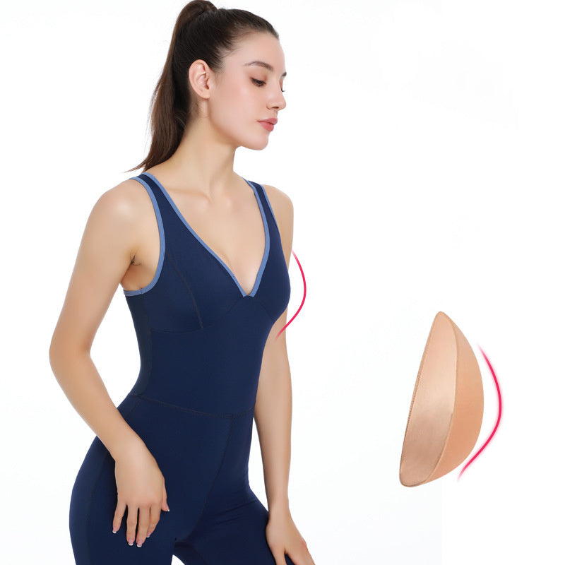 Woman wearing navy blue yoga bodysuit with V-neck and light blue trim, fitness activewear with removable padding