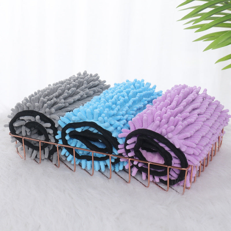Three rolled microfiber pet towels in gray, blue, and purple in a copper wire basket on a white surface