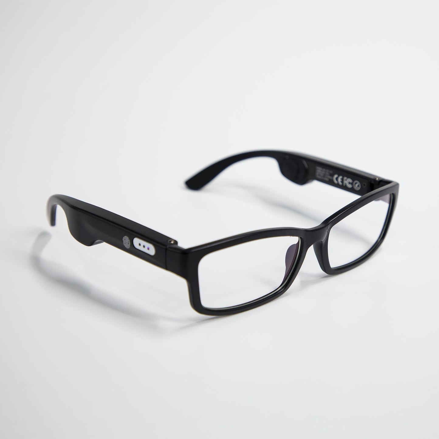 black smart glasses with clear lenses and integrated Bluetooth controls on white background