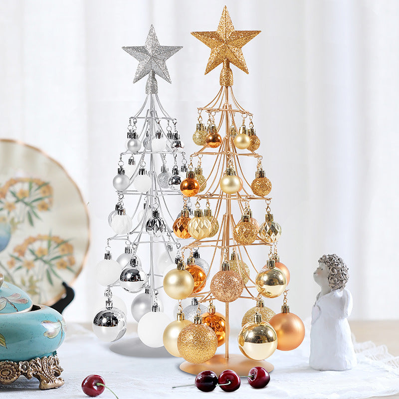 Modern bronze and silver metal Christmas tree ornaments with star toppers and gold, silver, and bronze baubles on table
