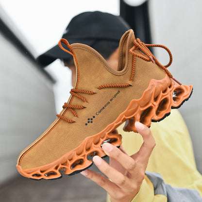 Brown men's leather sneaker with orange textured sole and laces held by person in casual outdoor setting