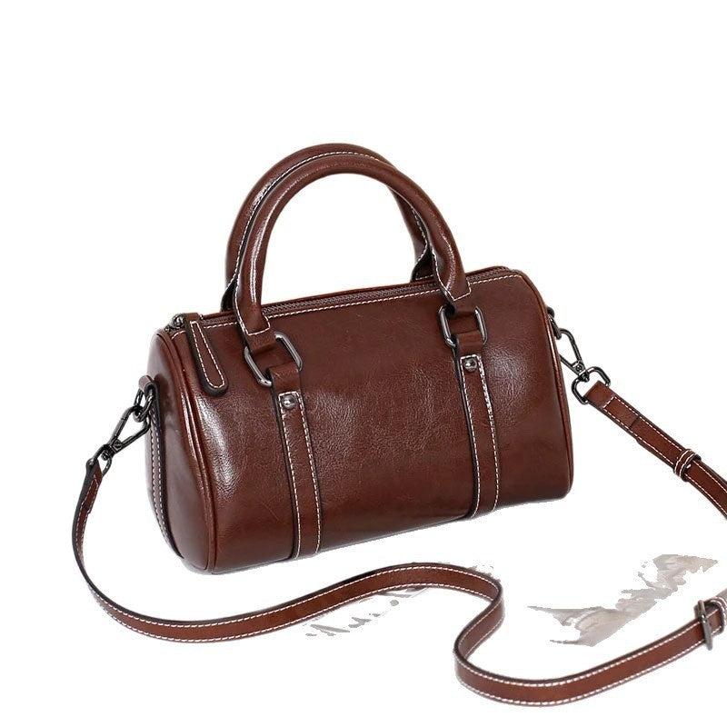 Caramel brown leather crossbody bag with top handles and detachable strap on white background