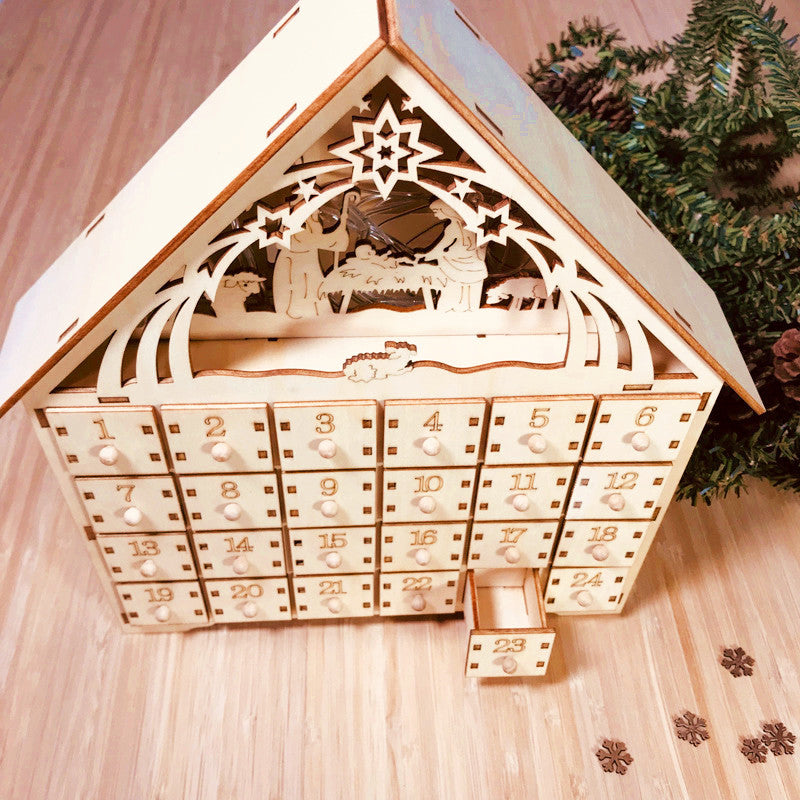 Wooden DIY Christmas advent calendar shaped like a house with nativity scene cutouts and numbered drawers