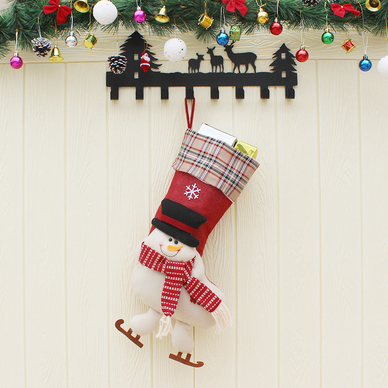 Red Christmas stocking with snowman design hanging on festive black reindeer wall hanger under colorful Christmas garland