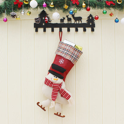 Red Christmas stocking with snowman design hanging on festive black reindeer wall hanger under colorful Christmas garland