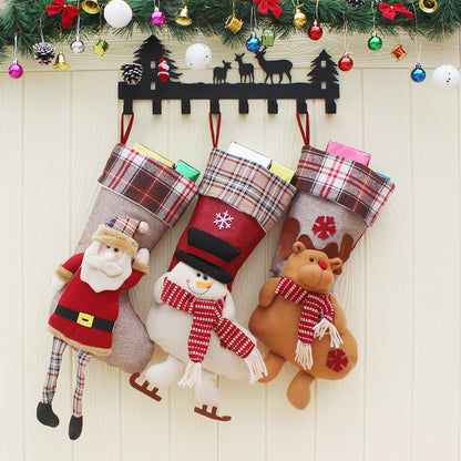 Christmas stockings with Santa, snowman, and reindeer plush decorations hanging on festive wall hook with greenery and ornaments