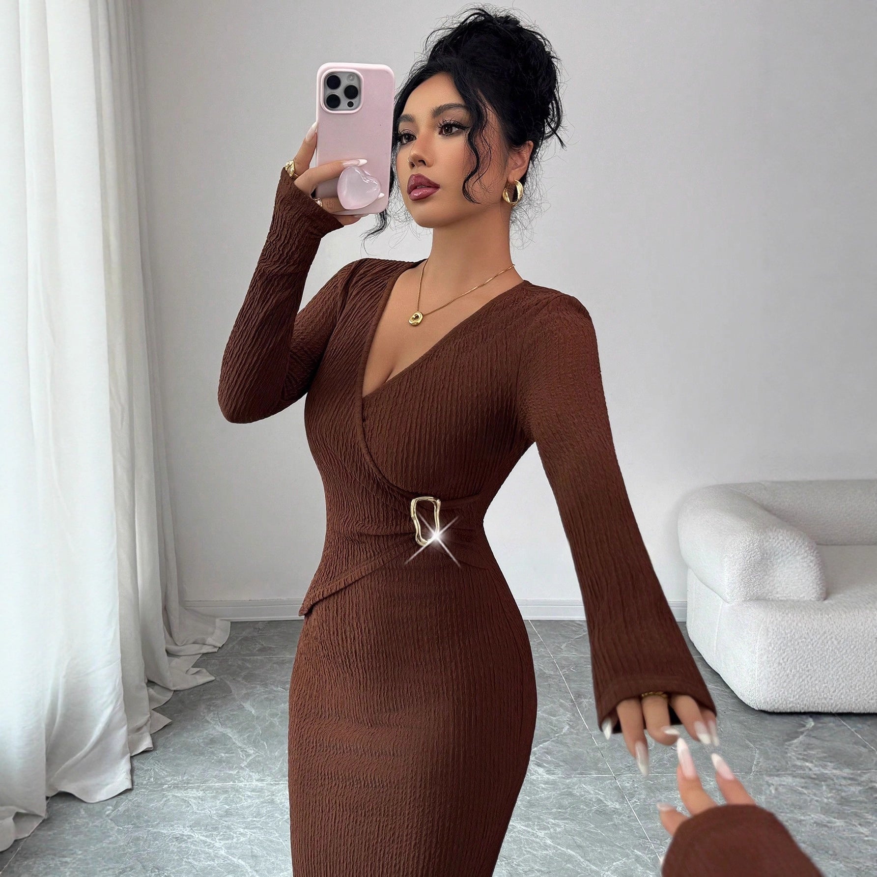 Woman taking mirror selfie wearing coffee brown ribbed knit dress with gold buckle detail