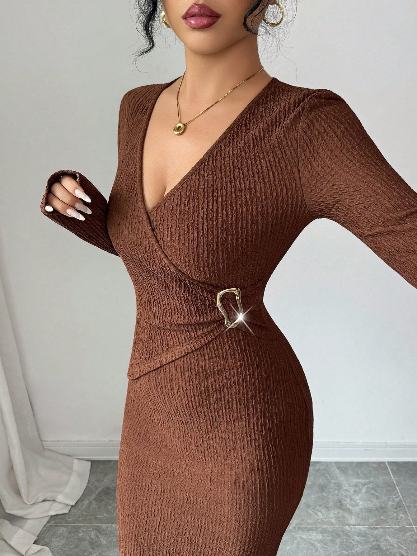 Woman in coffee brown textured knit dress with long sleeves and gold side buckle detail