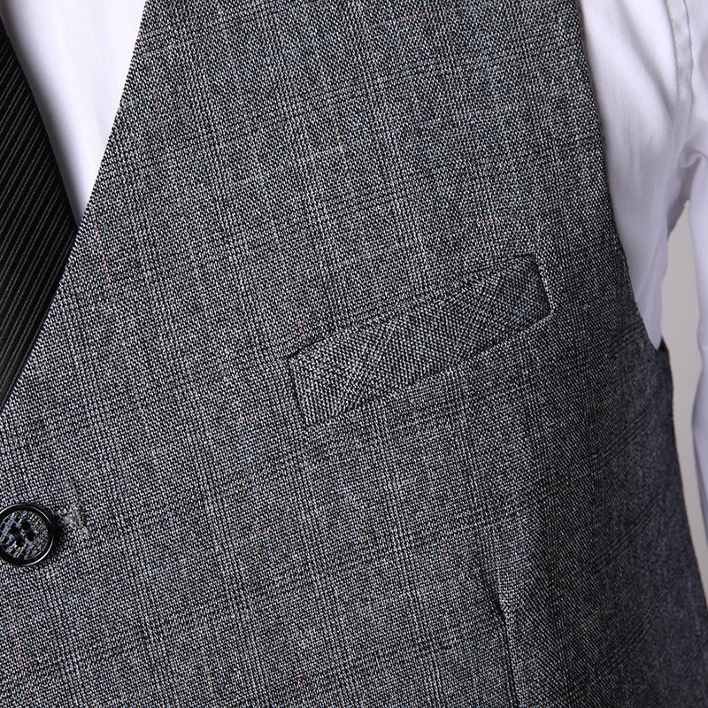 Close-up of men's grey textured three-piece suit vest over white shirt with black striped tie