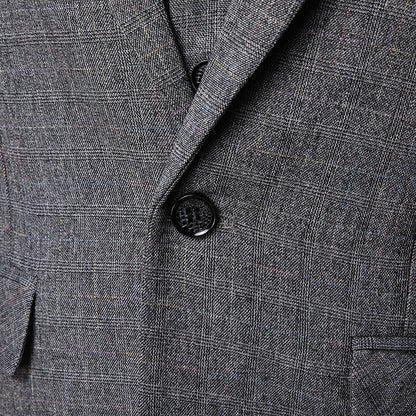 Close-up of men's gray plaid suit jacket with black button and notch lapel detail