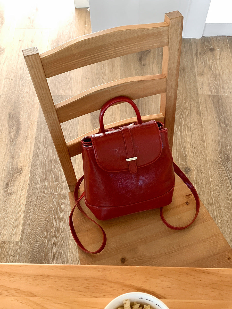 Red leather small backpack on a wooden chair with wood flooring background