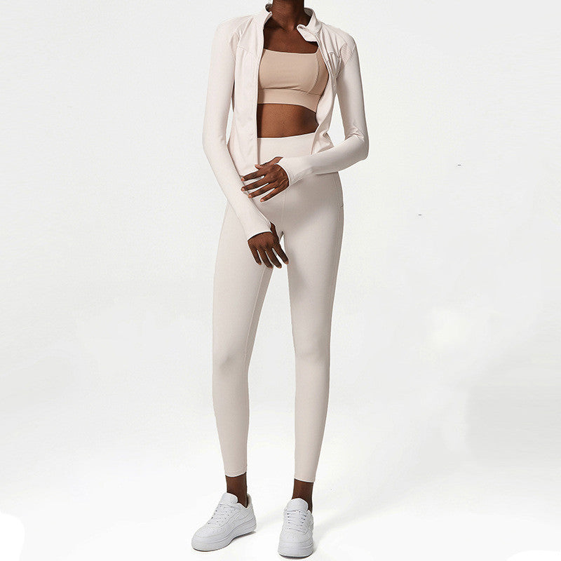 Woman wearing beige two-piece activewear set with long-sleeve jacket and white sneakers on white background