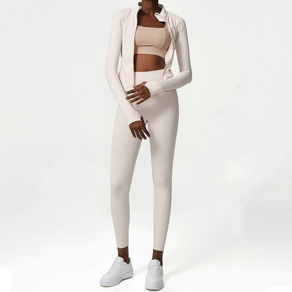 Woman wearing beige two-piece activewear set with long-sleeve jacket and white sneakers on white background