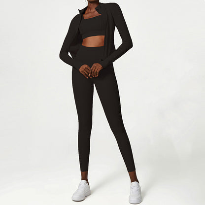 Woman wearing black sports bra, leggings, and zip-up jacket with white sneakers on white background