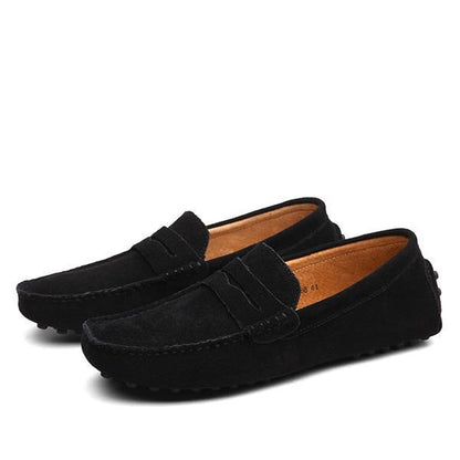 Pair of black men's suede driving loafers with penny strap and rubber pebble soles on white background